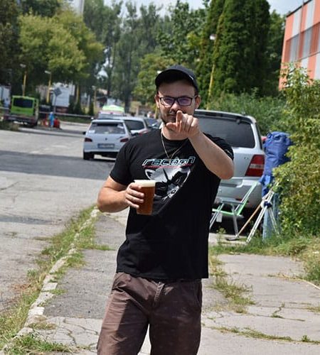 příchozí pozitivně naladěn muž držící pivo v ruce je oděn do trička s logem Racoon